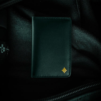 Dark green leather wallet with a logo on a dark background