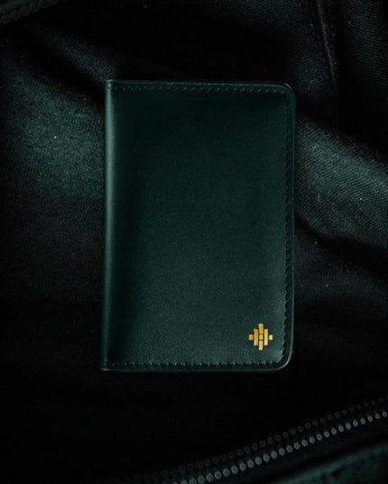 Dark green leather wallet with a logo on a dark background